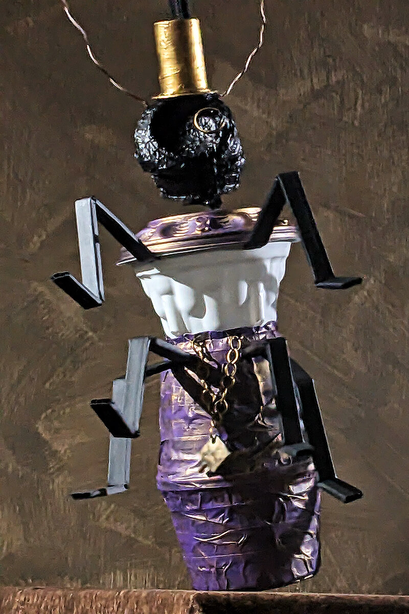 A puppet Banker from the movie "Red Flag of the Future". The puppet wears a gold top hat and appears to be dancing.